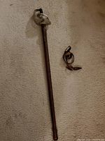Full-length sword in scabbard alongside carrying strap on carpet