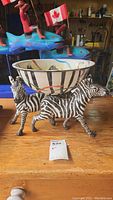 Full assembled view of enamel bowl atop zebra stand on wood surface