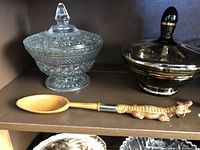 Three items: clear textured glass lidded bowl, black and gold glass lidded dish, souvenir spoon with alligator handle