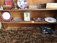 Shelf with variety of vintage decorative plates and crystal items displayed