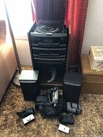 Full view of the stereo system with two speakers and cameras with cases arranged in front on carpeted floor.