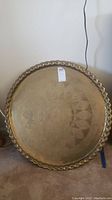 Front view of large round solid brass tray with etched patterns and scalloped border