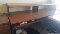 Full view of laminate desk showing upper shelf, main surface, and slide-out keyboard shelf with some visible office items beneath the desk.