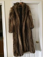 Full length shot of the long fox fur coat hanging on a hanger showing its overall length and fur texture.