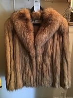Front view of fox fur jacket hanging showing full natural brown fox fur and collar.