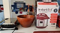 Photo showing Instant Pot box, wooden bowl, and Hamilton Beach grill on countertop