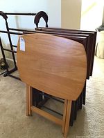 Tray tables stacked on metal stand showing wood grain and shape