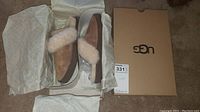 Photo of the slippers in the box with tissue paper, showing the intact packaging and slippers side view.