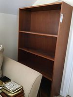 Front angle view of the bookcase showing the top three shelves and side panel with visible wear and scratches.