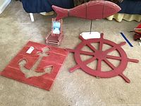 Photo showing all four wooden nautical themed decor items: square anchor cutout board, ship wheel, fish on stand, Adirondack frame.