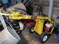 Side profile of yellow auger unit mounted on two wheels with engine at rear