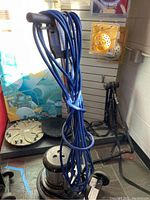 Upright view of floor buffer with blue cord coiled around handle and buffer head