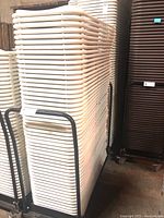 Stack of white plastic folding chairs loaded on black metal cart