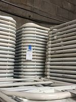 Large stack of white folding chairs with lot tag visible