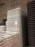 Tall stack of white molded plastic folding chairs against concrete block wall