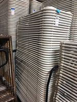 Stack of folded white plastic chairs shown from side