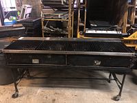 Front view of commercial charbroiler grill showing cast iron grates, stainless steel surround, tubular steel frame and caster wheels