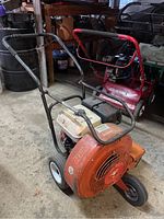 Front three-quarter view showing tubular handlebar, blower housing and engine mounted on frame