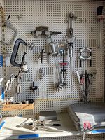 Overview of assorted metal clamps and separators mounted on pegboard