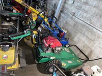 Green Outback brush cutter among other power tools, angled side view