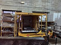 Yellow scaffold frames on rack with stacked planks and pipes in foreground