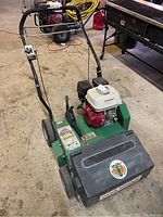 Front view of overseeder showing engine, hopper and handlebar