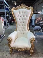 Front view of white and gold throne chair showing tufted back and carved gold frame