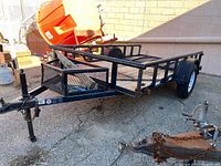 Overall view of the utility trailer showing frame, deck and axle
