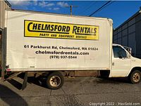 Driver side view of white box truck with Chelmsford Rentals decals