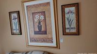 Framed floral artwork set displayed on wall, showing central large piece and one smaller side piece