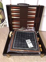 Opened wooden case showing backgammon board inside and separated black vinyl board on top of pieces
