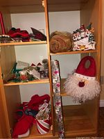 Shelved items showing Christmas decorations including candles, wrapping paper, stockings, ribbons, ceramic plaque, door knob hanger, and linens.