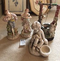 Front view of the four figurines including two porcelain children, ceramic boy with dog, and the wishing well.