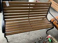 Front view of garden bench showing wood slats and metal frame with curved armrests and legs.