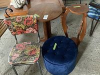 View showing entire lot including blue velvet pouf, vintage floral chrome kitchen chair, round wooden side table, and wooden plant stand.