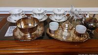 Overview of Royal Albert China cups and saucers and silver plate items on display surface