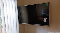 Full view of the LG 43-inch TV mounted on the wall near window blinds, black flat screen and silver bezel visible.