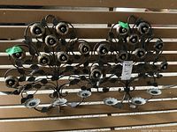 Pair of heavy metal floral wall art candle holders displayed on wooden slats. Ornate design with multiple flowers and leaves, each holding candle cups.