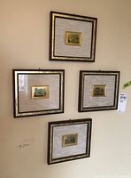 Four framed metallic plaques hanging on the wall in a group, showing the scale and framing style.