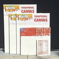 Full view of five assorted artist canvases, four are sealed in original packaging labeled 'The Art District' and one smaller canvas labeled 'Artist's Canvas'
