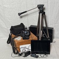 Full lot view showing FujiFilm digital camera with lens, black camera bag, three batteries, GT-400P tripod, NIX digital frame, power adapter, remote, and box.