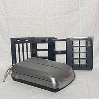 Epson Perfection 4990 scanner with three black plastic film holders placed behind it
