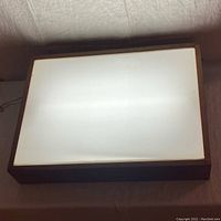 Front view of the light box illuminated to show the glowing effect of the light diffuser panel inside the hardwood frame.