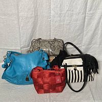 Four purses and two pairs of black gloves arranged on white cloth background
