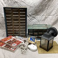 Front view of two parts cabinets, outdoor lantern sconce, safety strap kits, electrical cords, and miscellaneous hardware arranged on cloth background