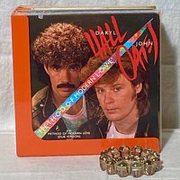 Close-up image of a vinyl record album featuring Hall & Oates Method of Modern Love single with a metallic skull ashtray placed to the side.
