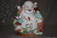 Front view of a seated porcelain Buddha with five children figurine