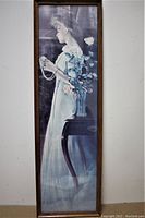 Full view of the large tall framed print of a girl next to a vase of flowers.