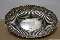 Front view of oval sterling silver dish showing gadrooned interior and floral pierced border