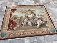 Full view of the tapestry laid flat, showing the entire design including the urn, grapes, flowers, and detailed border.